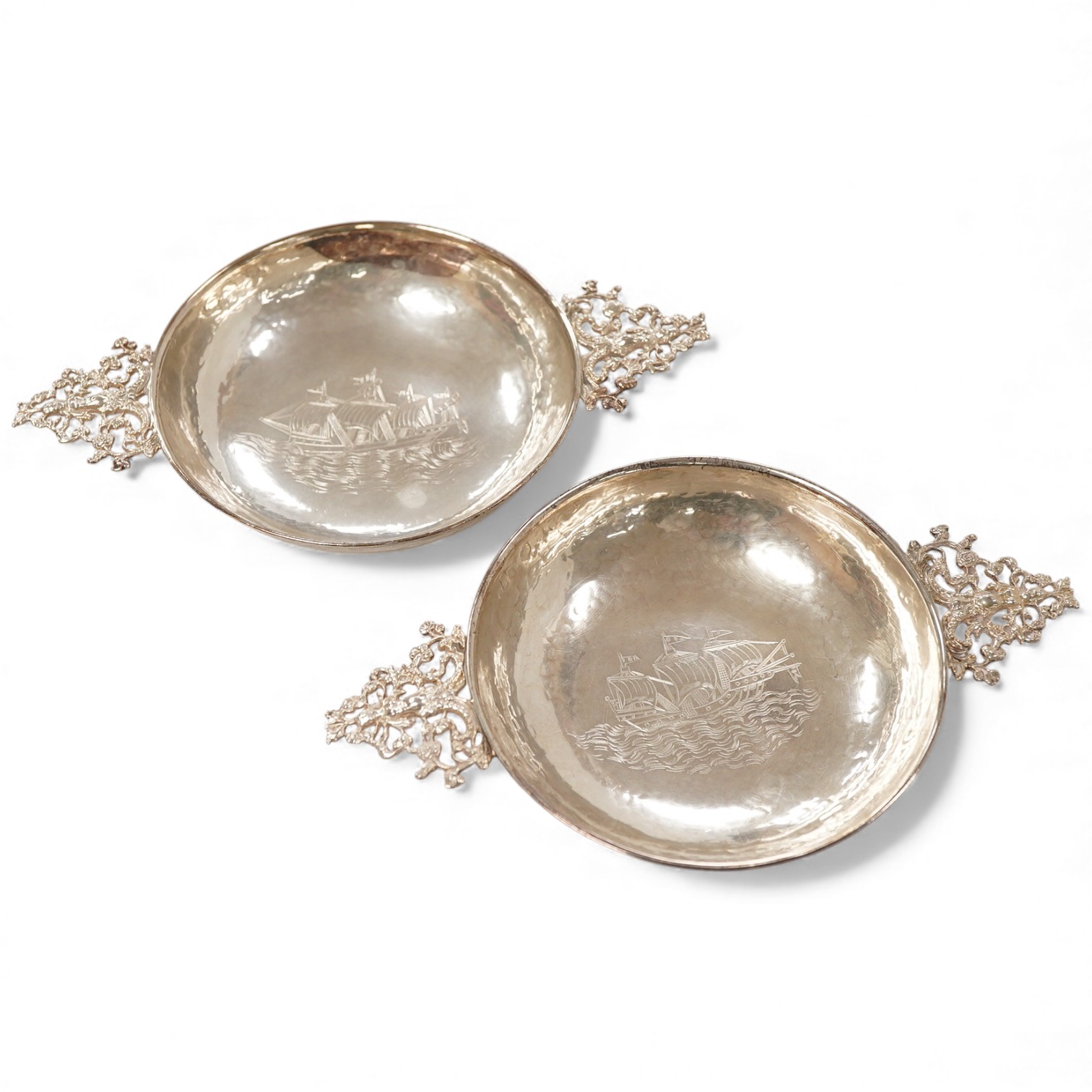 A pair of George V continental silver quaichs, with pierced lug handles and each engraved with a three-masted ship at sea, import marks for Berthold Hermann Muller, London, 1913, 17.3cm.
